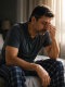 Tired middle-aged man rubbing his eyes while sitting on the bed next to an alarm clock and a note reading "8 Hours of Sleep", illustrating that sleep duration does not guarantee sleep quality.